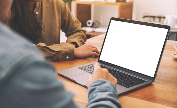 Two people with a laptop on a wooden table