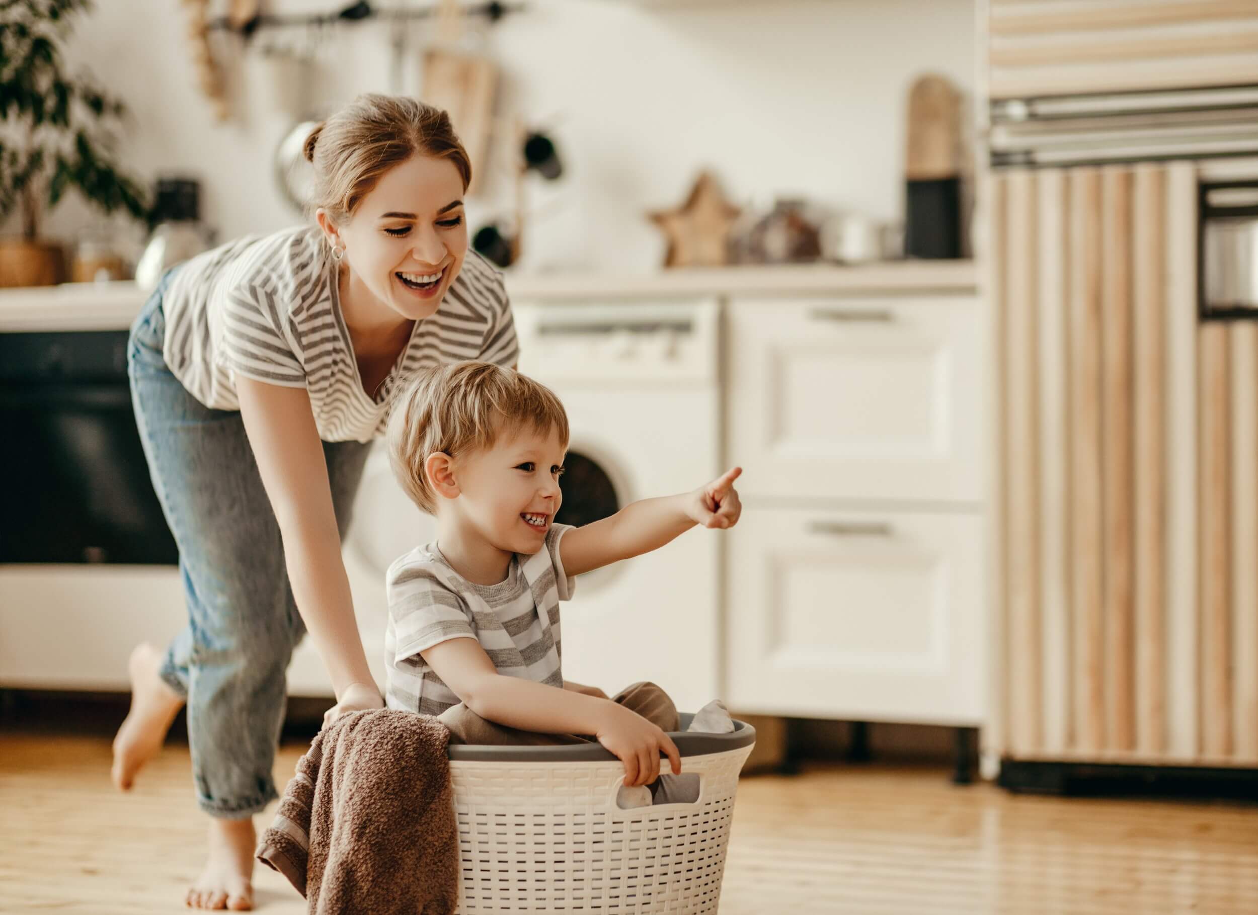 Mom and son have fun with a basket in the kitchen