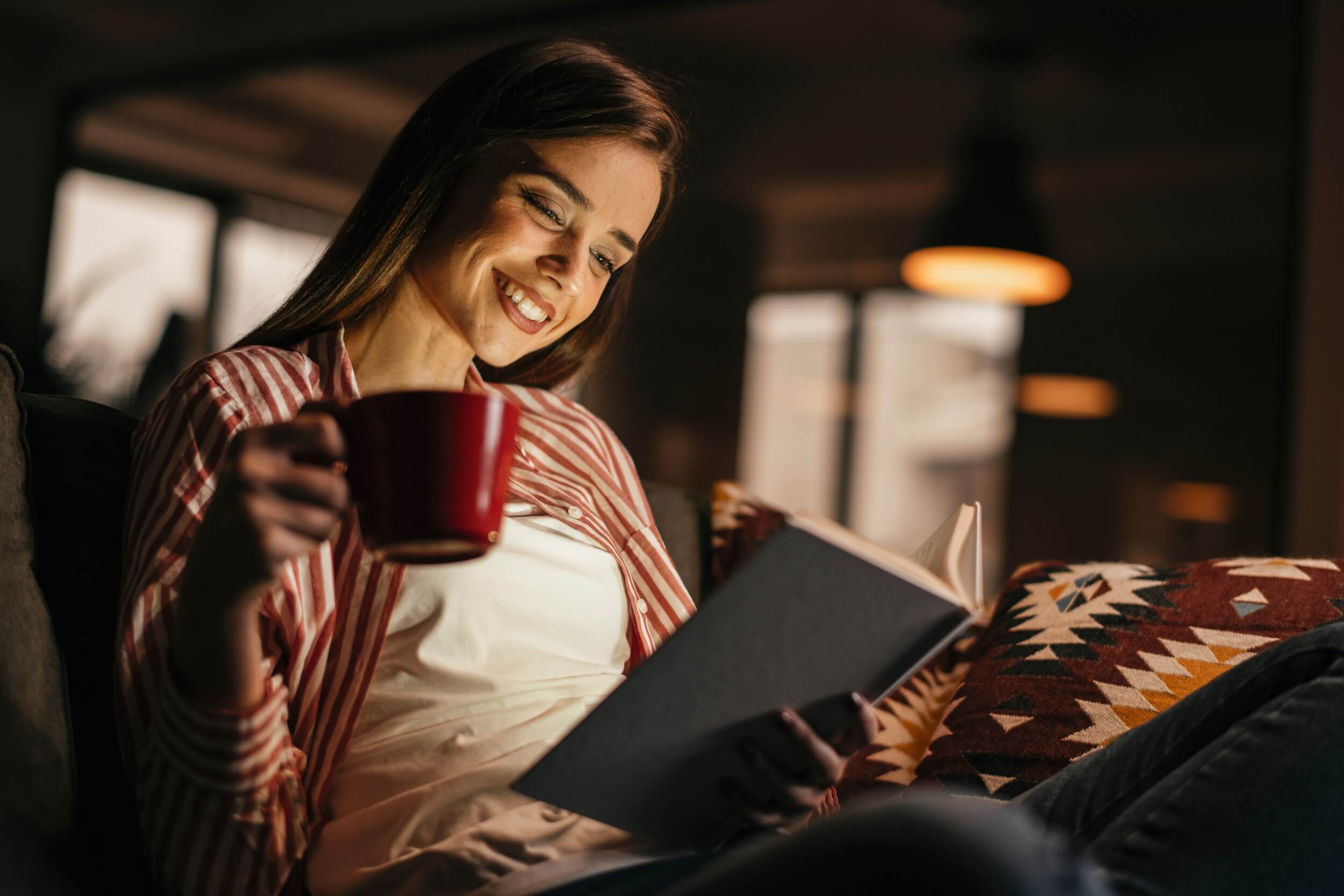 Young woman reading a book while drinking coffee