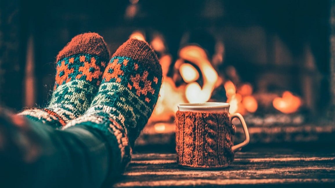 Feet in front of a fireplace and a cup next to them Feet in front of a fireplace and a cup next to them