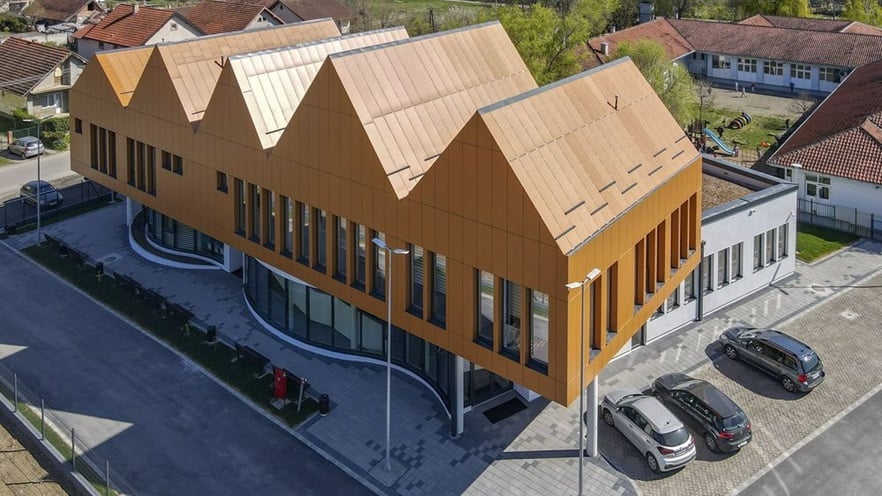The building has two floors, the ground floor is round shaped in the front and the top floor is shaped like a series of  houses