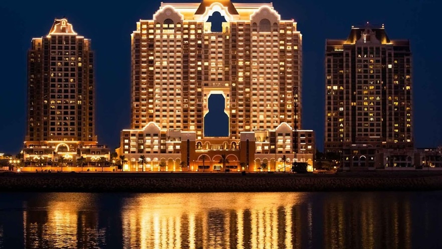 The largescale residential building's lights reflect in the water