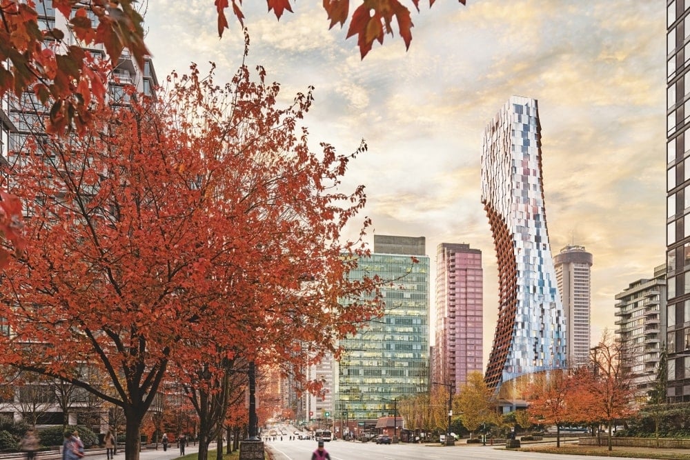 The tower in between other buildings and trees with red leaves
