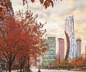 The tower in between other buildings and trees with red leaves