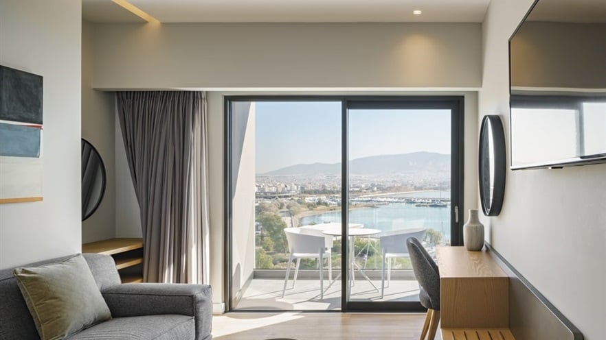 The sitting area of the room with a sofa and a desk, the window is closed