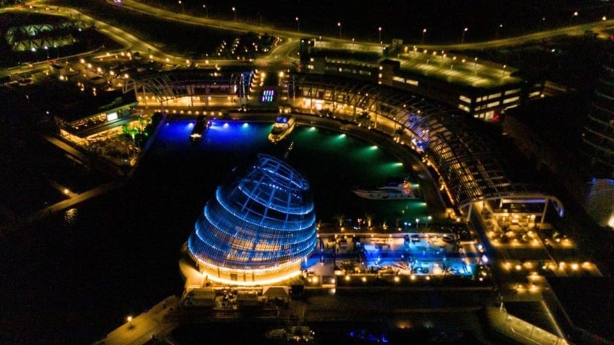 The marina with lights on at night, the Event Center stands out with the blue lighting