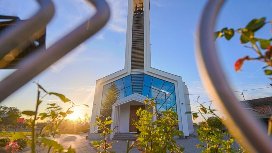 The church seen from behind flowers with the sun setting at the back