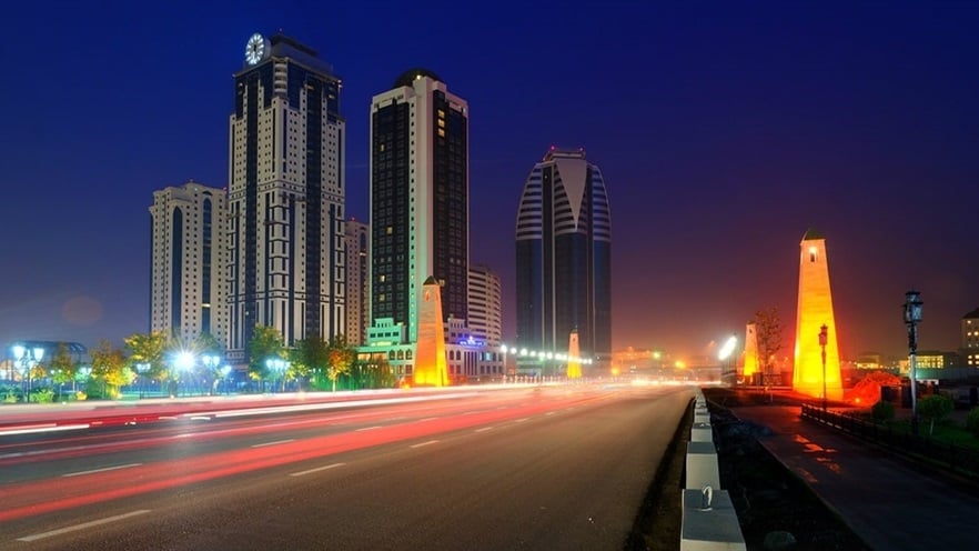 The street next to the buildings with traffic at night