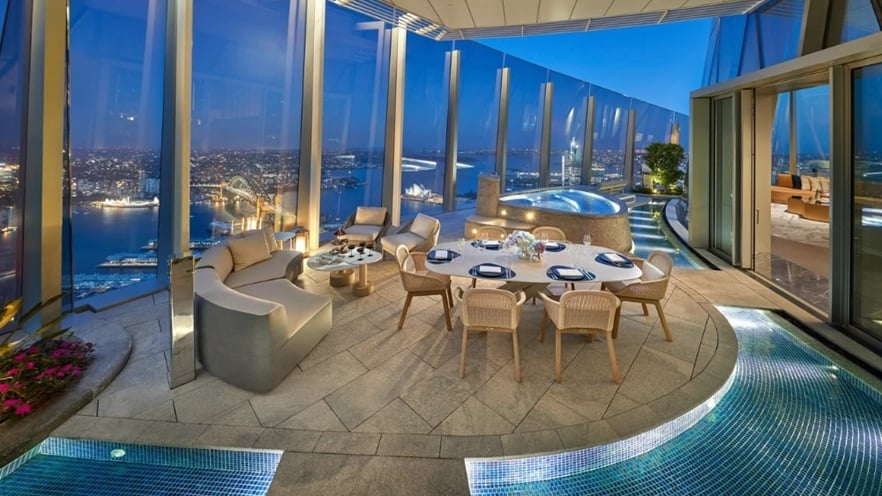 Outdoor area of Crown Sydney featuring landscaped greenery, seating spaces, and the curved glass façade of the tower in the background
