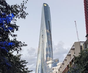 Crown Sydney tower with its distinctive twisting glass façade and reflective aluminum framing, rising prominently against a clear blue sky