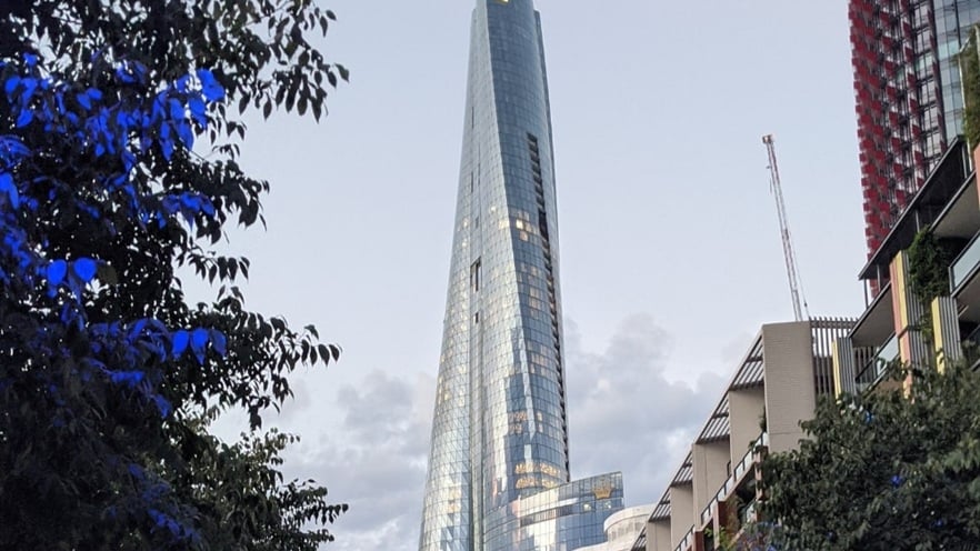 Crown Sydney tower with its distinctive twisting glass façade and reflective aluminum framing, rising prominently against a clear blue sky