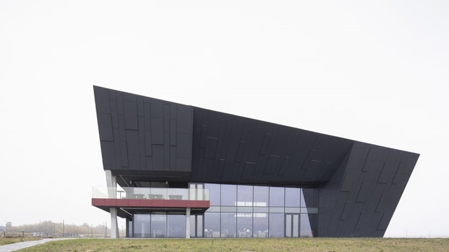 The side of the building has a large glass façade at the bottom and cladding on the top