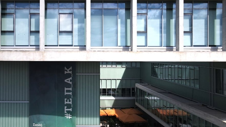 Facade of the Cyprus University of Technology building featuring a combination of solid concrete walls and large aluminum-framed curtain wall sections with clear glass panels