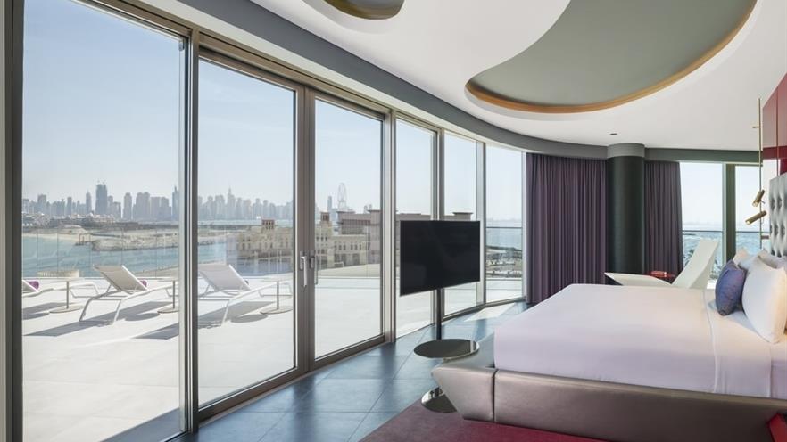 The bedroom with large glass openings and a large balcony with sunbeds