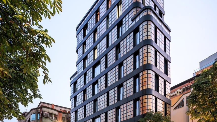 Golden Reflection building showcasing its bold, modern façade with large aluminum curtain walls, yellow-tinted glass panels, and a mix of recessed and protruding volumes