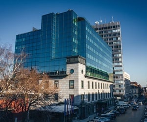The building is located on a busy street with parked cars and trees