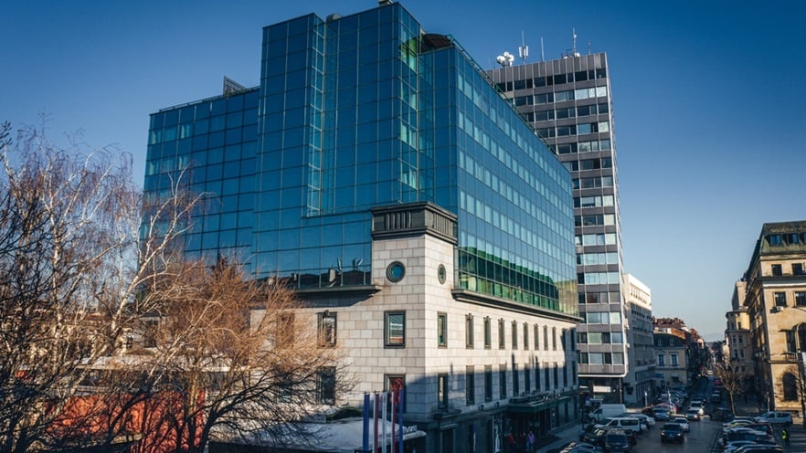 The building is located on a busy street with parked cars and trees