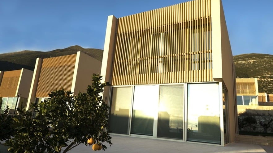 The house has large windows on the lower level and shading on the upper level
