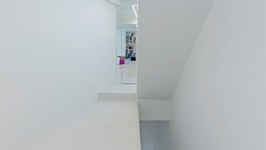 White corridor with colorful sitting room in the back