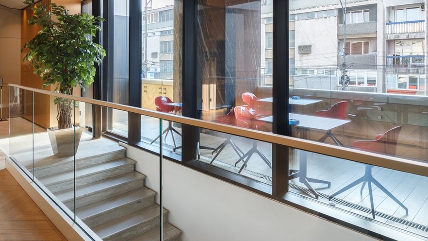 A staircase by the window and a balcony with tables & chairs