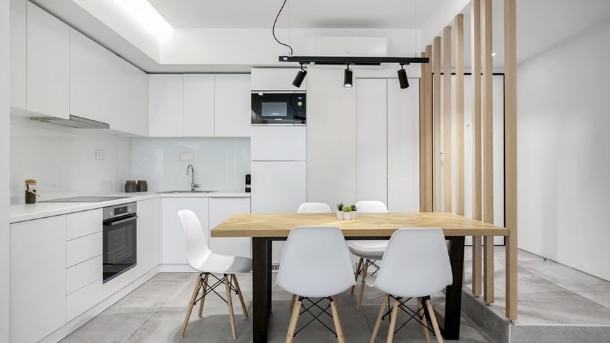 Corner kitchen counter and a table in the middle in white and wood tones
