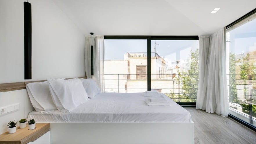 The bedroom has large windows on two sides