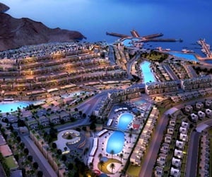 Aerial view of Il Monte Galala Resort featuring modern buildings and pools under the night blue sky.