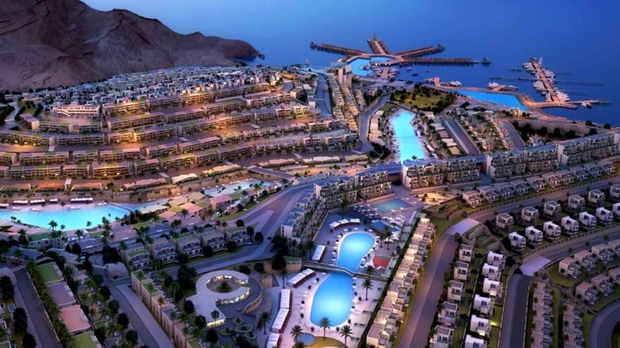 Aerial view of Il Monte Galala Resort featuring modern buildings and pools under the night blue sky.
