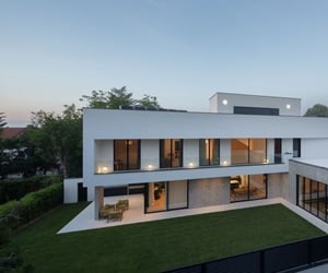 The building has three storeys with large windows and a lawn garden.