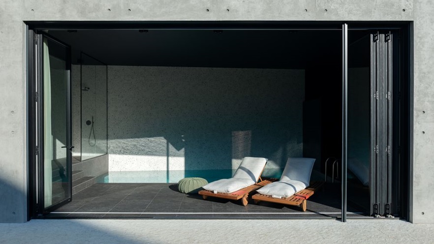 The open folding doors help integrate the indoor pool to the outdoor area