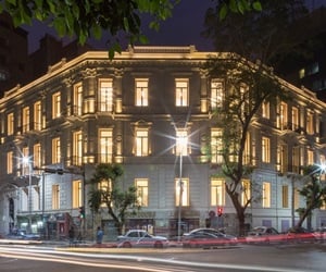 The building with lights on and traffic in the front