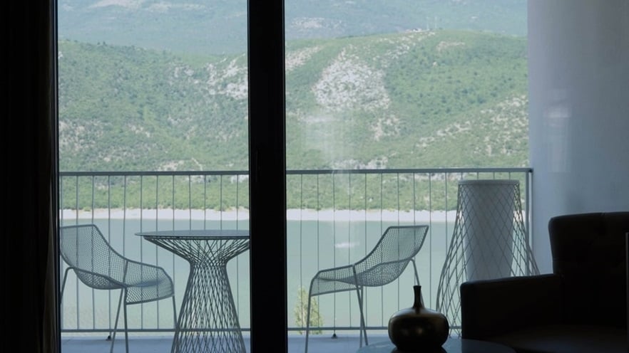 The room's balcony has metal furniture and a view of the lake