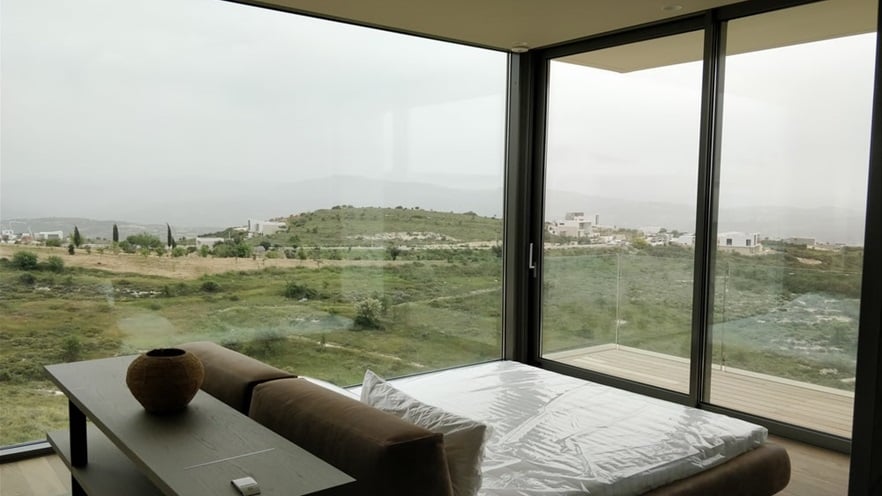The master bedroom has large glass openings on all sides and oversees the hills