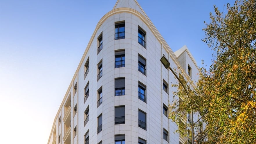Corner view of Mozart Residence showing its modern architecture with beige cladding, aluminum windows, and balconies