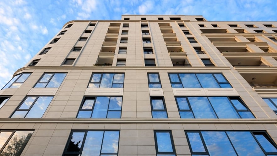 Front façade of Mozart Residence featuring large aluminum-framed windows and balconies, set against a beige exterior with clean, modern lines