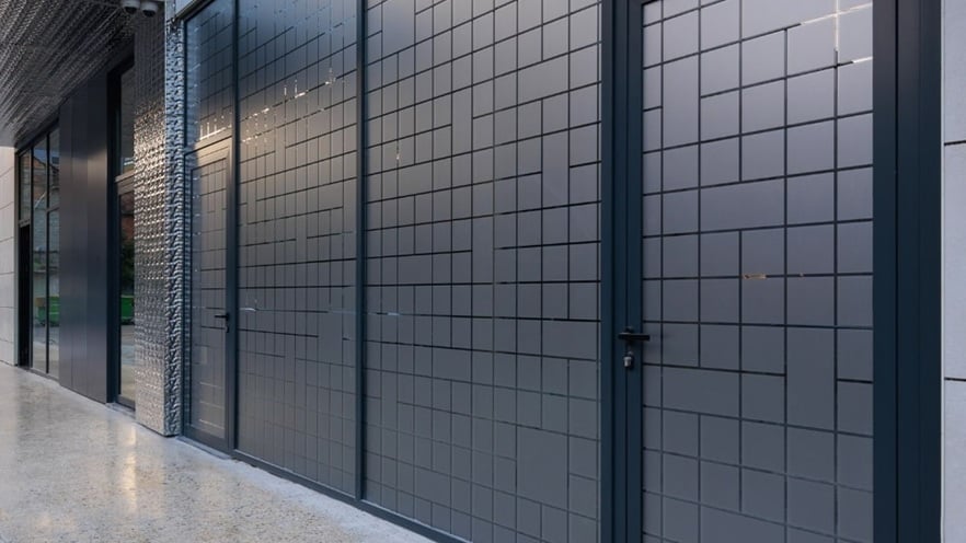 Close-up of aluminum curtain wall and door at Mozart Residence, featuring frosted glass and sleek dark frames
