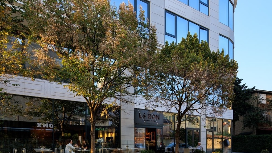 Ground floor of Mozart Residence featuring a modern café with large glass windows and minimalist outdoor seating