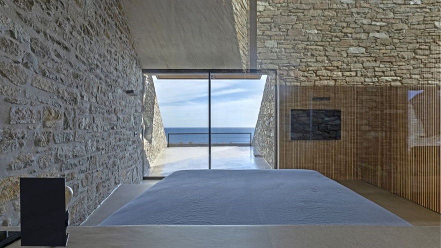 The bedroom has stone walls and a window with sea view
