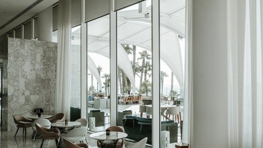 The indoor sitting area in earth tones, overlooking the outdoor through large windows