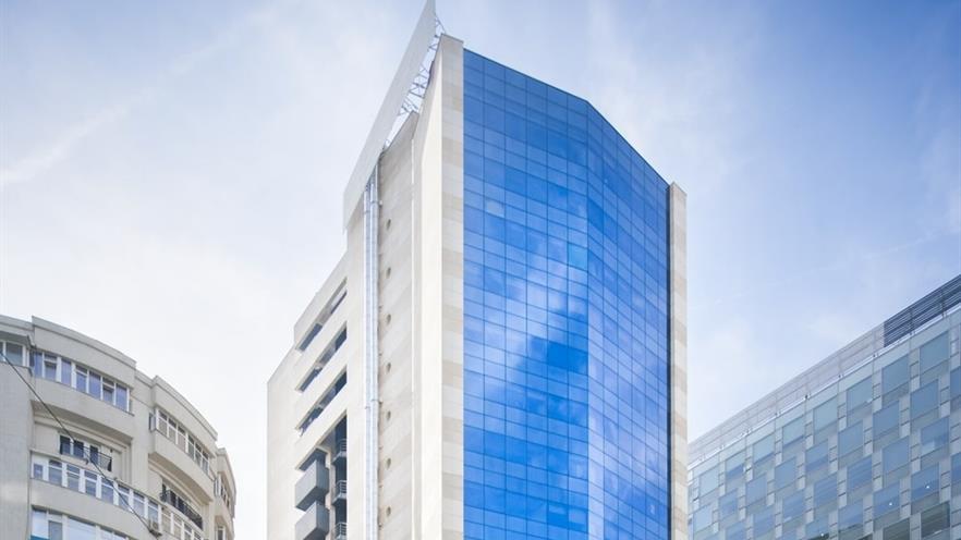 The building has a glass façade and a side with cladding and balconies