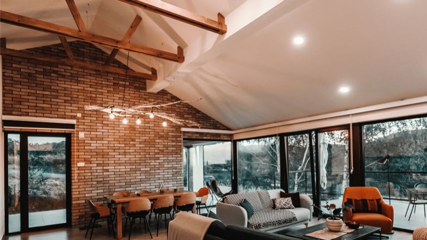 The living room with a sitting area and a dining area, with a brick wall