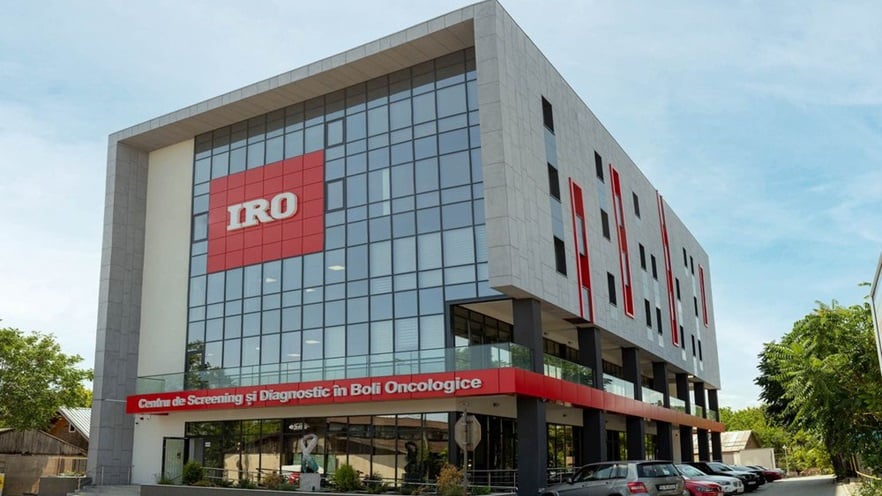 The multi-storey building has curtain wall and cladding on the façade, with red signs