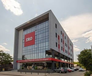 The building has a large curtain wall façade at the front with a large red sign