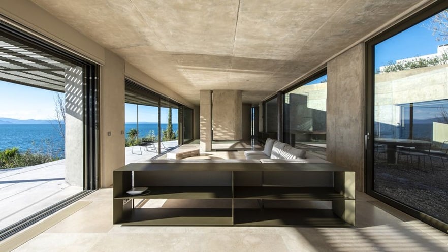 The living room is minimal, with a large couch and window openings on both sides