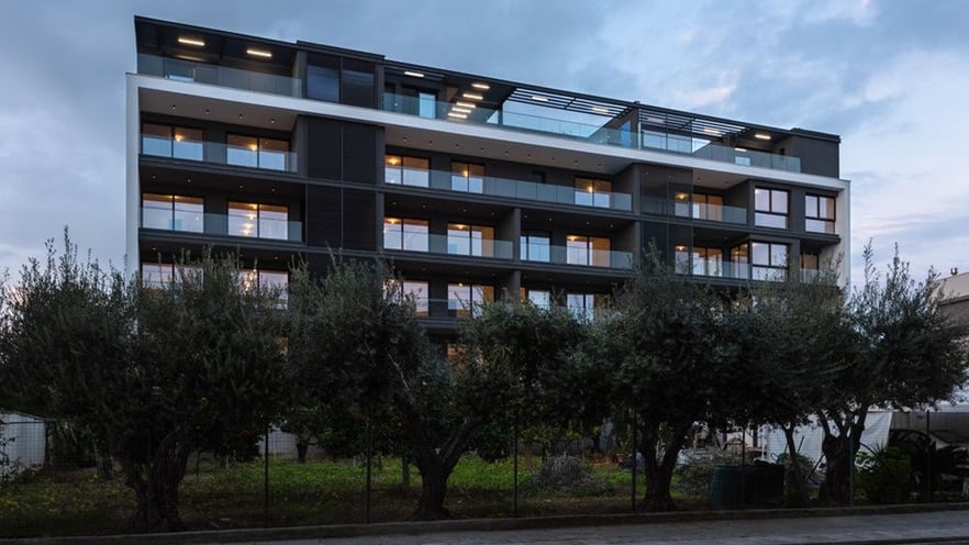 The building has large verandas and balconies and a garden with olive trees
