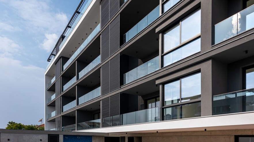 The building's facade is glass railings, louvers and glass openings from floor to ceiling at each storey