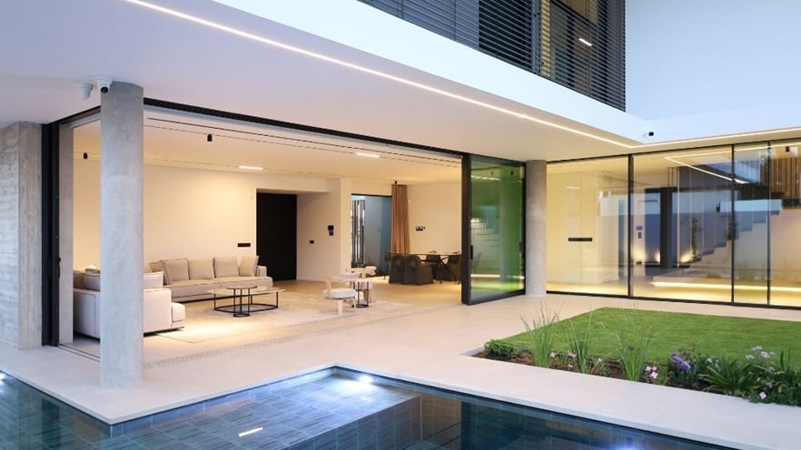 Modern house with open-plan living area, aluminium sliding doors, lawn, and swimming pool.