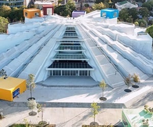 The building has a pyramid shape. The sides alternate between staircases and curtain walls. There are also some randomly placed colorful square rooms.