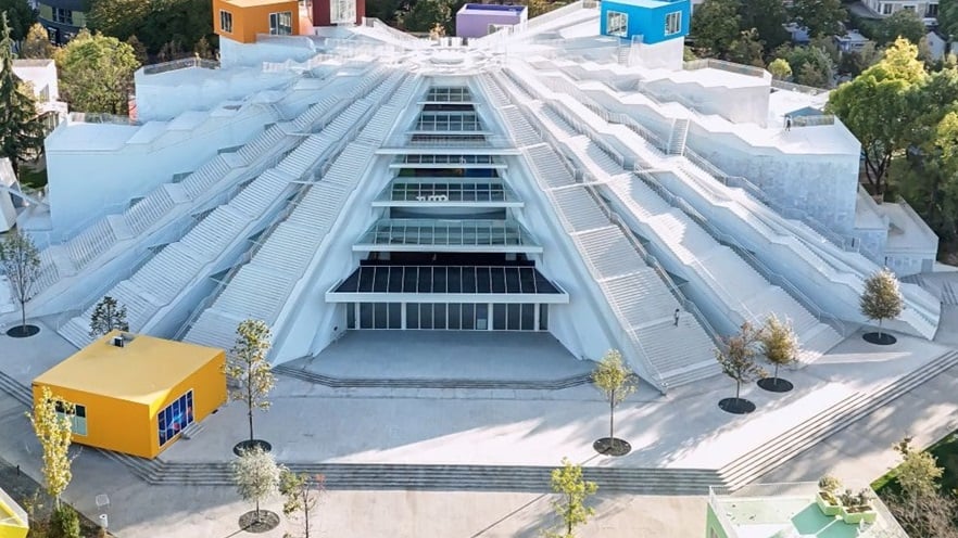 The building has a pyramid shape. The sides alternate between staircases and curtain walls. There are also some randomly placed colorful square rooms.