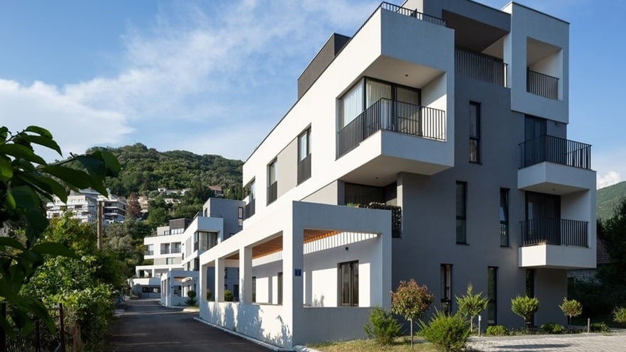 The four-storey building has many windows and balconies and uneven surfaces all around